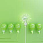 Six green lightbulbs in a row on a green background. The fourth lightbulb is raised slightly higher than the rest and is switched on with the word 'idea' lit up inside of it.